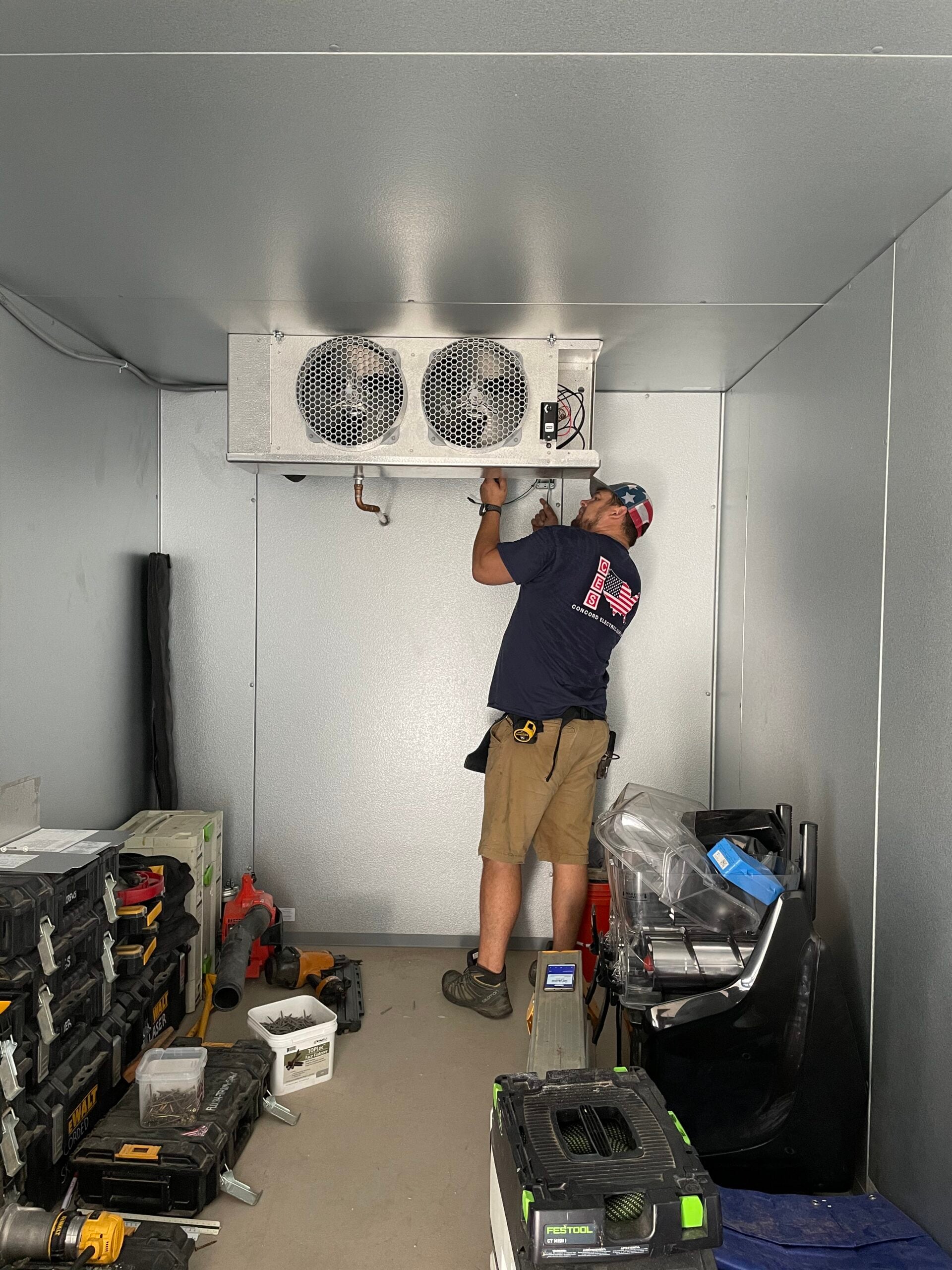 Electrician installing an HVAC unit in a residential setting, surrounded by various tools and equipment.
