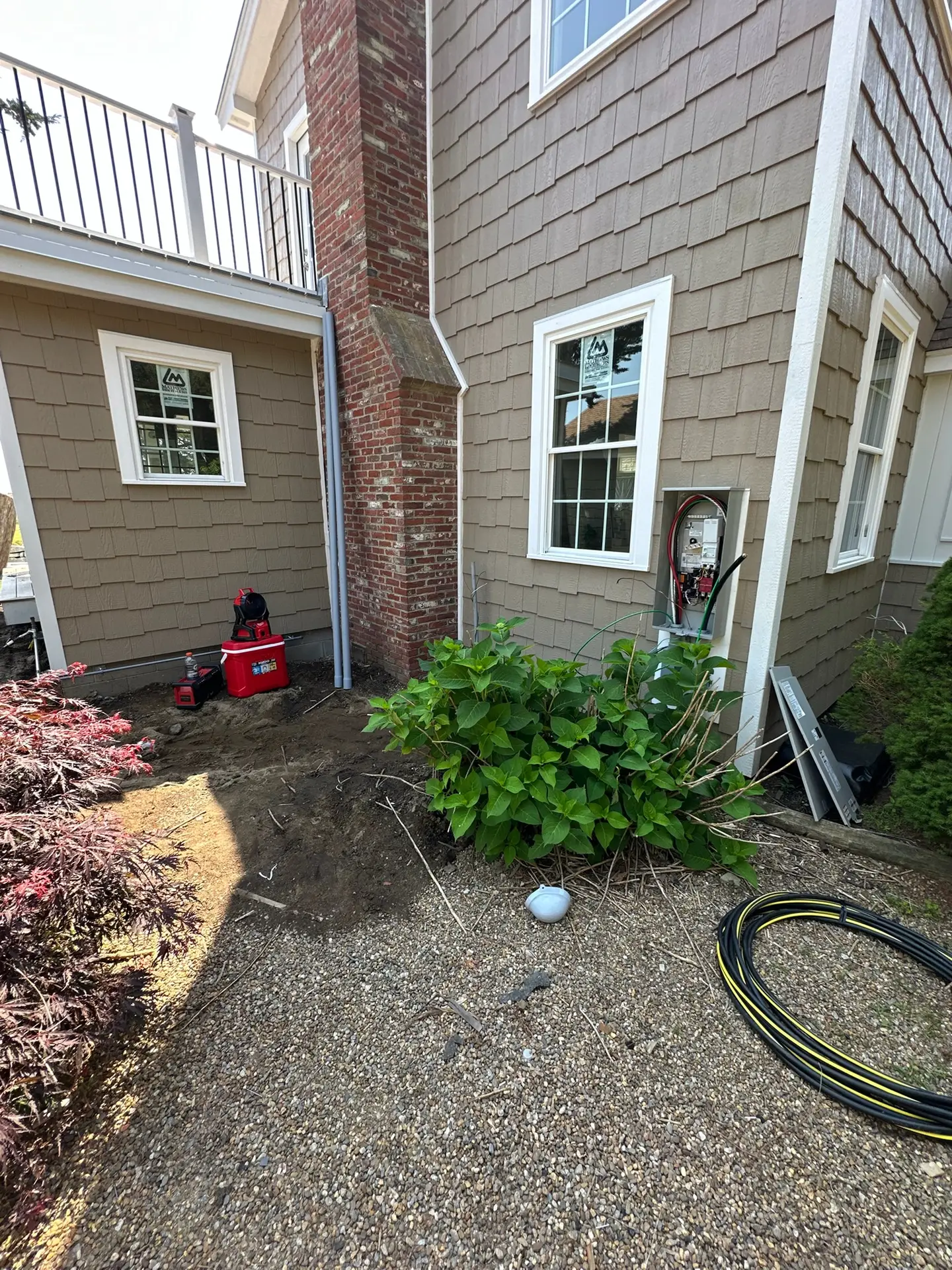 Residential electrical repair site in Plaistow, NH, featuring a service panel, tools, and landscaping elements, highlighting Moore Electric's diagnostic approach to electrical issues.