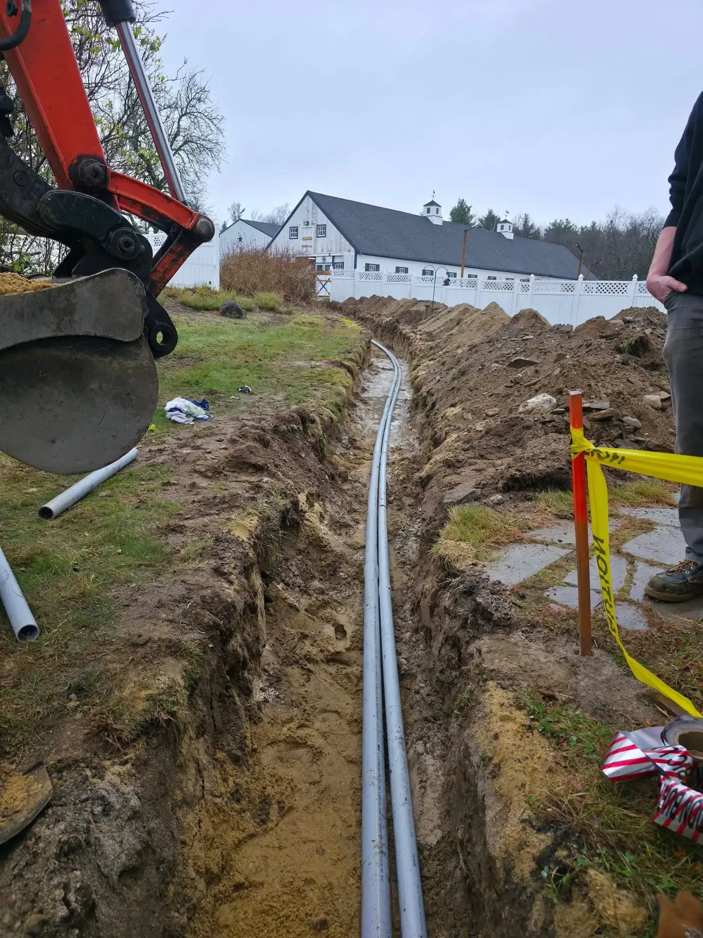 Excavated trench for generator installation with electrical conduit and construction equipment, showcasing preparation for utility connections in Plaistow, NH.