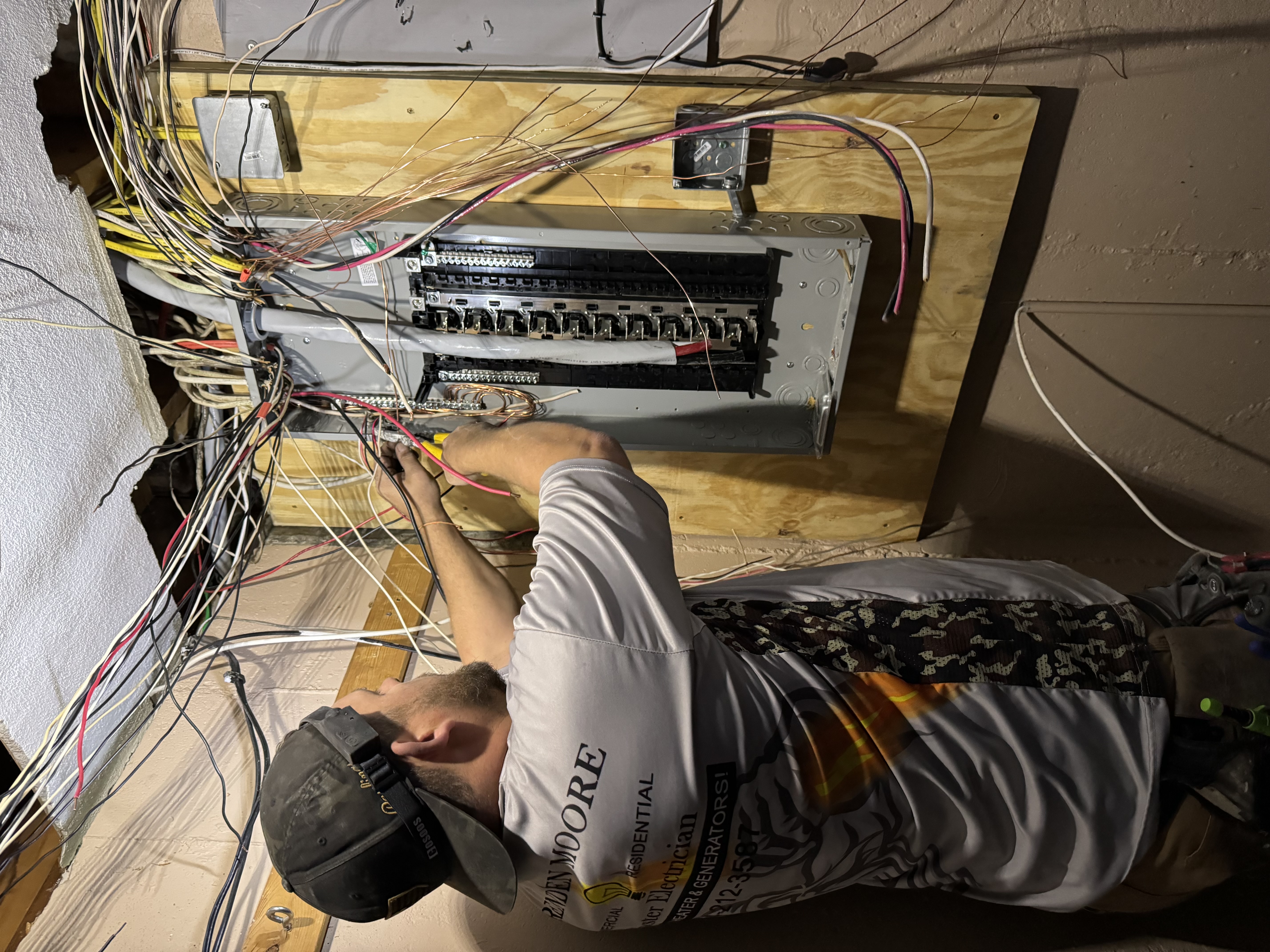 Electrician working on residential electrical panel upgrade, surrounded by colorful wires, emphasizing electrical service and safety.