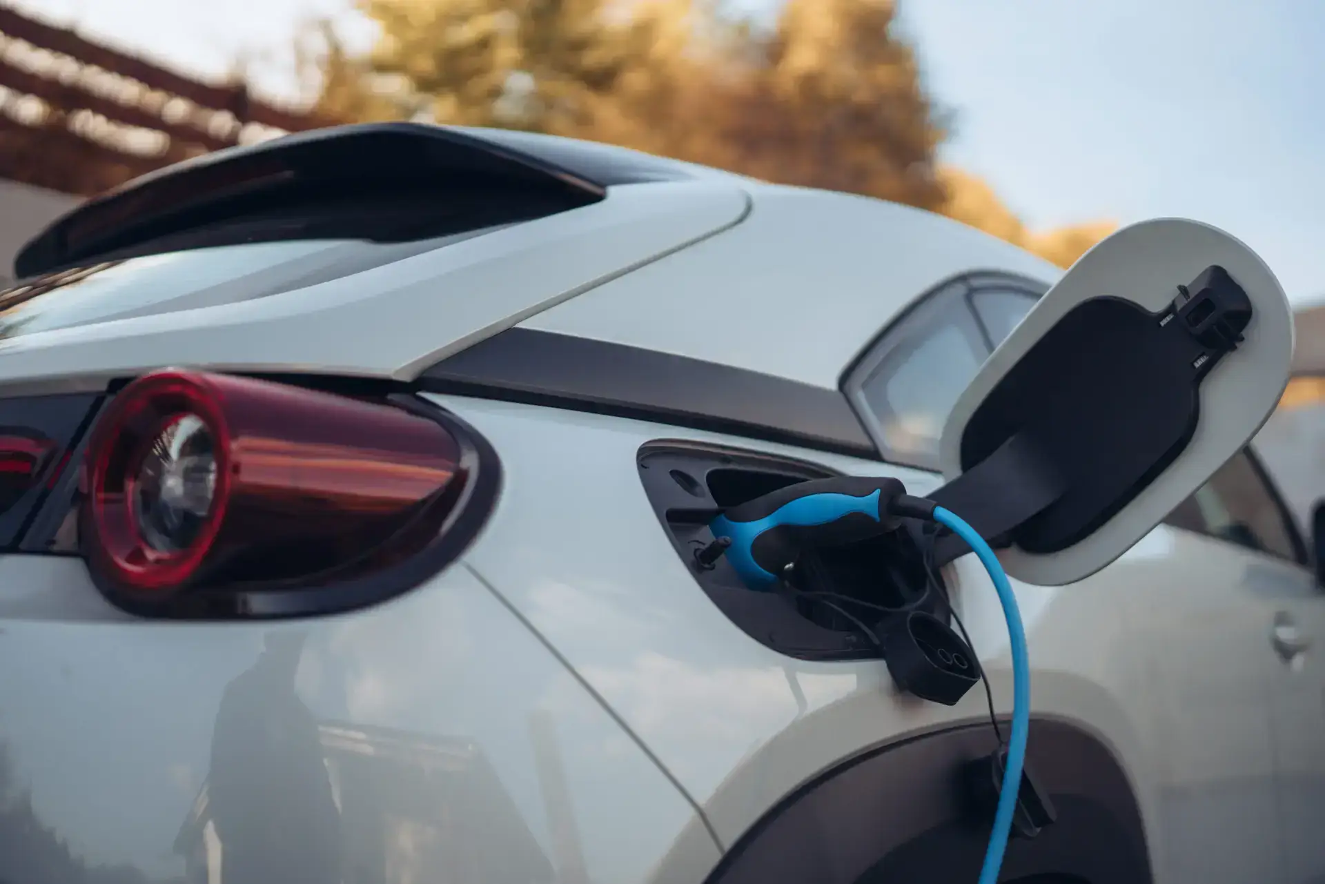 Electric vehicle charging station with a blue charging cable plugged into a car, showcasing home EV charging capabilities relevant to Moore Electric's installation services in Plaistow, NH.