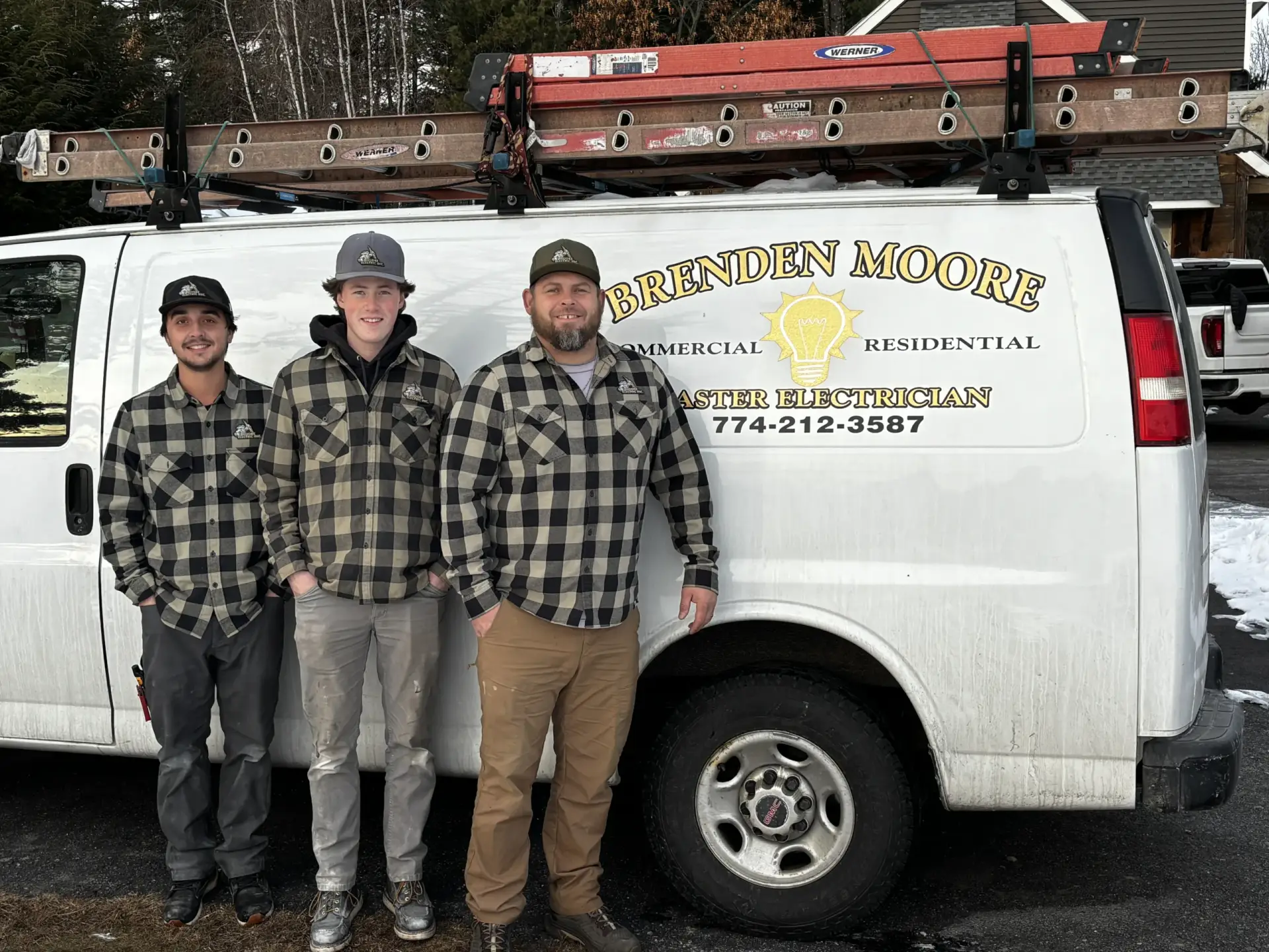 Three electricians in plaid shirts standing in front of a service van with "Brenden Moore Master Electrician" logo, showcasing reliable electrical repair services for residential and commercial needs.