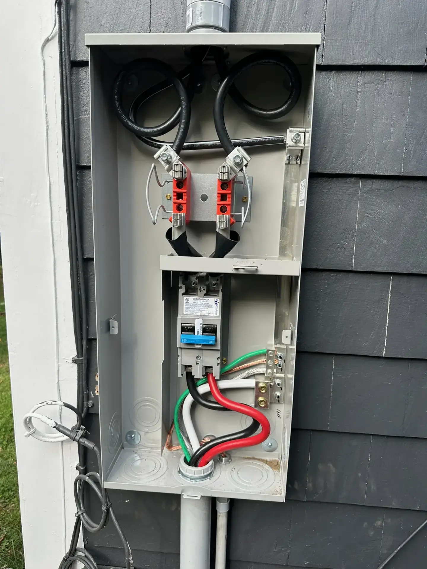 Electrical service panel with wiring connections and circuit breakers, showcasing installation details relevant to electrical work in Plaistow, NH.