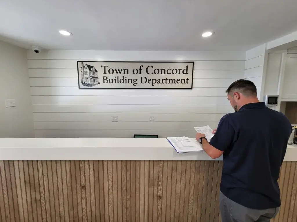 Master electrician submitting electrical panel upgrade permit application at a New Hampshire building department
