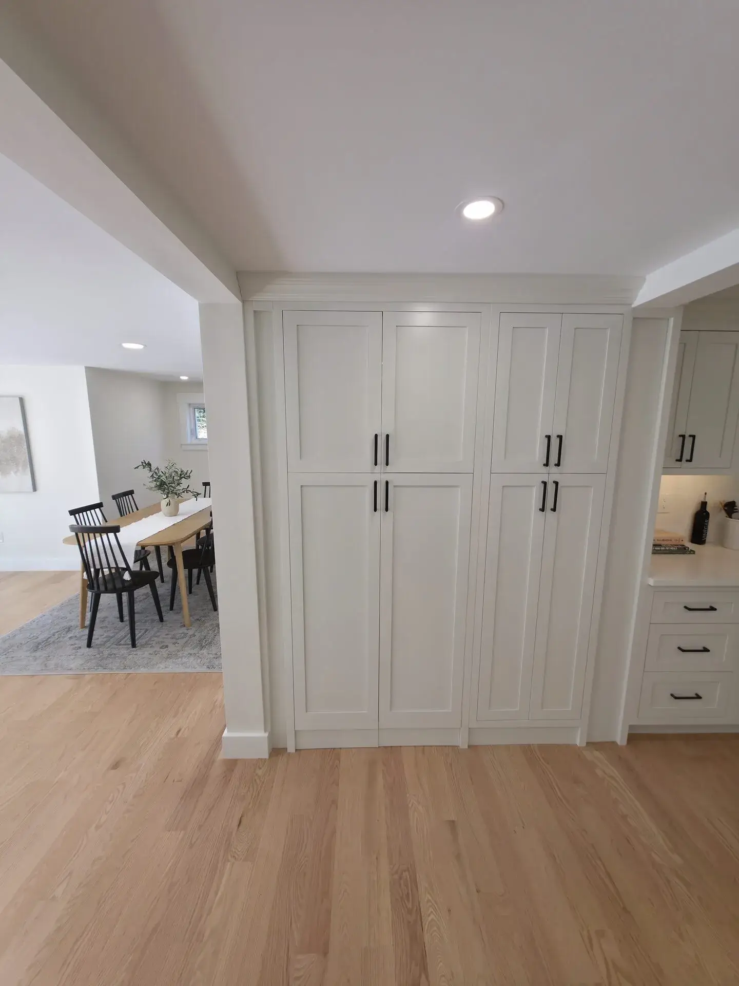 Modern kitchen with white cabinetry and a dining area visible in the background.